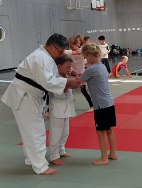 Eine Judotrainerin erklärt zwei Kindern die Griffhaltung